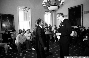 ["Senator John D. (Jay) Rockefeller speaks with a man before addressing a room full of people in the Senate."]%