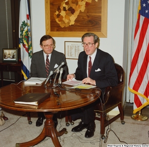 ["Senator John D. (Jay) Rockefeller sits at a small desk in his office with another man during a press event for a math and science bill."]%