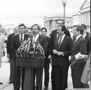 ["Senator John D. (Jay) Rockefeller stands behind a man speaking at a press event outside the Senate."]%