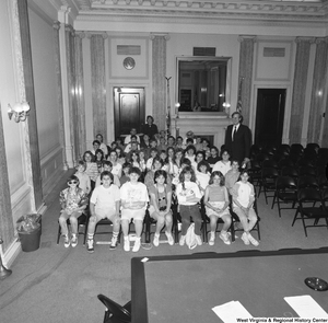 ["Senator John D. (Jay) Rockefeller stands next to a group of students in a Senate room."]%
