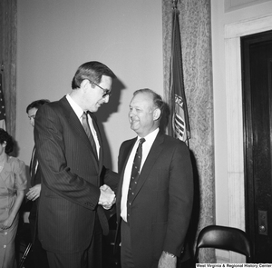 ["Senator John D. (Jay) Rockefeller smiles and shakes hands with an unidentified man in one of the Senate buildings."]%