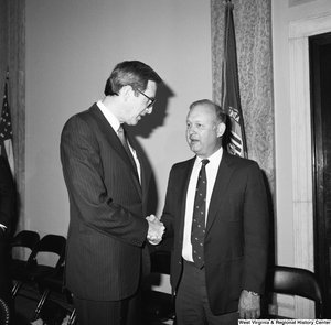 ["Senator John D. (Jay) Rockefeller shakes hands with an unidentified man in one of the Senate buildings."]%