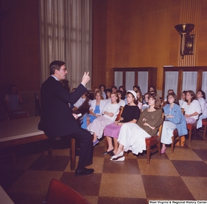 ["Senator John D. (Jay) Rockefeller speaks to a seated group of unidentified female students in one of the Senate buildings."]%