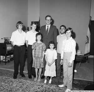 ["Senator John D. (Jay) Rockefeller stands in his office with a man and five students from a Christian school in West Virginia."]%