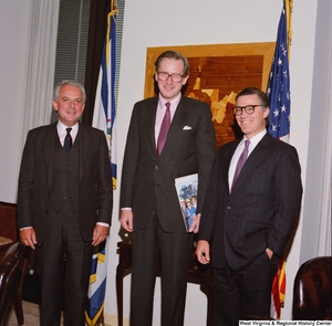 ["Senator John D. (Jay) Rockefeller stands with two men in his office."]%