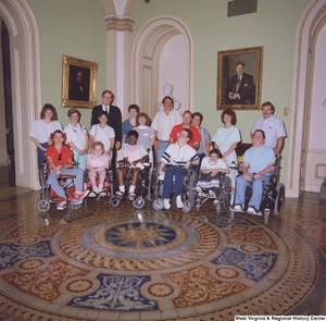 ["Senator John D. (Jay) Rockefeller stands for a photograph with a large group in a rotunda."]%
