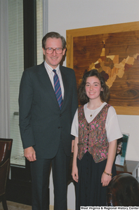 ["Senator John D. (Jay) Rockefeller stands beside a young woman, possibly an intern, in his office."]%