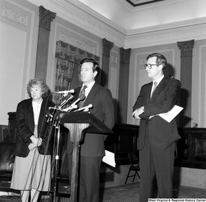 ["Senator John D. (Jay) Rockefeller and an unidentified woman stand behind Senator John Heinz as he speaks about the Dislocated Workers Improvement Act of 1987."]%