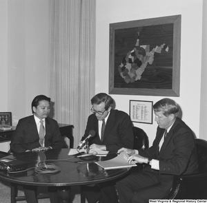 ["Senator John D. (Jay) Rockefeller signs his name on a document during a meeting with representatives from the US Steel Mining Company."]%
