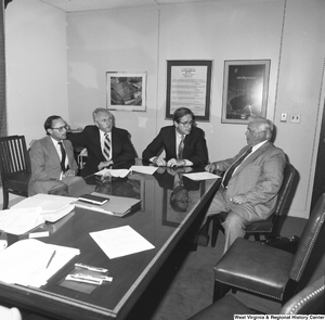 ["Senator John D. (Jay) Rockefeller sits with three unidentified men at a conference table in his office."]%