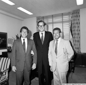 ["Senator John D. (Jay) Rockefeller links arms with two unidentified individuals in his office and poses for a photograph."]%
