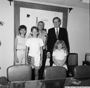 ["Senator John D. (Jay) Rockefeller stands with a family of four in his office."]%