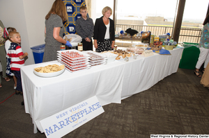 ["Several people stand behind the West Virginia Marketplace table at the celebration for the state's 150th birthday."]%