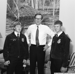 ["Senator John D. (Jay) Rockefeller stands with his hands on his hips between two students representatives of the Future Farmers of America."]%