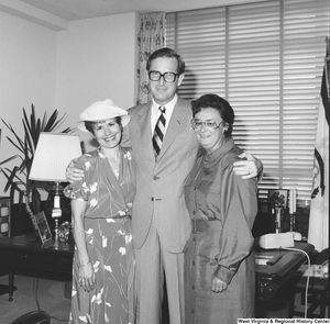 ["Senator John D. (Jay) Rockefeller poses for a photograph in his office with his arms around two unidentified individuals."]%