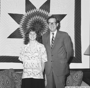 ["Senator John D. (Jay) Rockefeller and an unidentified individual pose for a photograph in front of the quilt that hangs in his Washington office."]%