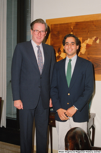 ["Senator John D. (Jay) Rockefeller stands next to a young man, likely an intern, in his office."]%