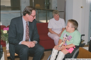 ["Senator John D. (Jay) Rockefeller sits and speaks to a young boy in a wheelchair."]%