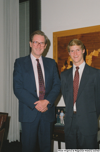 ["Senator John D. (Jay) Rockefeller stands next to a young man who appears to be an intern."]%
