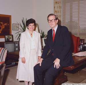 ["In this color photo, Senator John D. (Jay) Rockefeller sits on the edge of his desk with an unidentified woman."]%