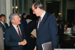 ["Senator John D. (Jay) Rockefeller laughs with a man before a hearing."]%