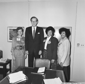 ["Senator John D. (Jay) Rockefeller stands next to three women who wear large badges that read \"The GFWC Free Enterprise Program\"."]%