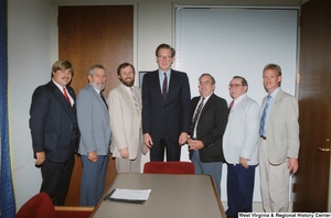 ["Senator John D. (Jay) Rockefeller stands with six unidentified men in the conference room of his office."]%