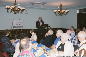 ["Senator John D. (Jay) Rockefeller speaks at a luncheon. The sign beside him reads \" Christopher J. Dodd Hosts the Connecticut Senior Research Program\"."]%
