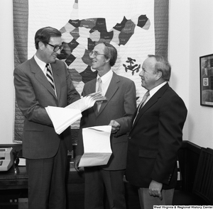 ["Senator Rockefeller smiles and holds a stack of papers with the County Commissioner from Marshall County, West Virginia."]%