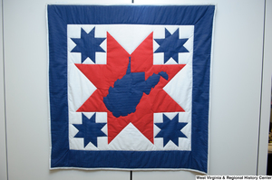 ["A red, white, and blue West Virginia quilt hangs on a wall in Senator John D. (Jay) Rockefeller's office."]%
