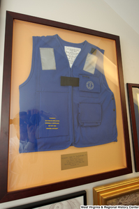 ["A life vest hangs on a wall in Senator John D. (Jay) Rockefeller's office. The plaque reads: \"Senator John D. Rockefeller IV, For all you do for our State and Nation on behalf of the employees of Mustang Survival Mfg. Inc. Ellizabeth, WV\"."]%