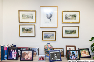 ["Many photographs and paintings hang on a wall and sit on a table in Senator John D. (Jay) Rockefeller's office."]%
