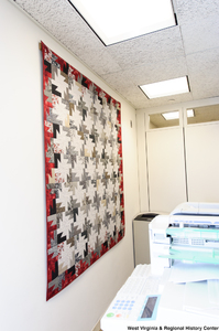 ["A quilt hangs on a wall behind a photocopier in Senator John D. (Jay) Rockefeller's office."]%