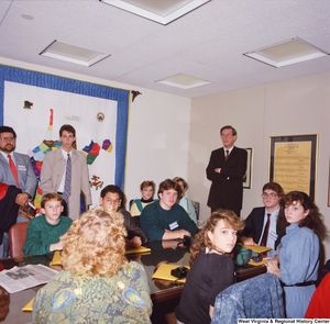 ["This color photograph shows Senator John D. (Jay) Rockefeller standing in his office behind a group of students in Close Up who sit around a table."]%