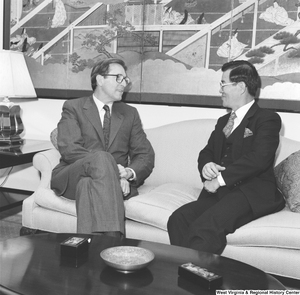 ["Senator John D. (Jay) Rockefeller sits on the couch in his office with an unidentified man."]%