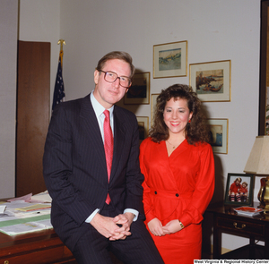 ["Senator John D. (Jay) Rockefeller sits on the edge of his desk next to an unidentified young woman."]%