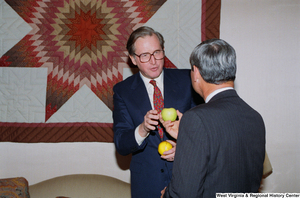 ["Senator John D. (Jay) Rockefeller holds a Florida orange and gives Florida Senator Bob Graham a West Virginia apple."]%