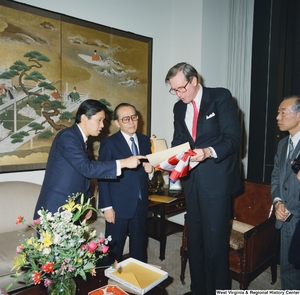 ["Senator John D. (Jay) Rockefeller receives a flag as a gift from the visitors in his office."]%