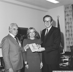 ["Senator John D. (Jay) Rockefeller, his wife Sharon, and author Christopher G. Janus, a West Virginia native, hold a copy of the author's novel, \"Miss 4th of July, Goodbye\". The novel is set in Montgomery, West Virginia and is based on the real-life experiences that Janus's sister had when she immigrated from Greece to West Virginia."]%