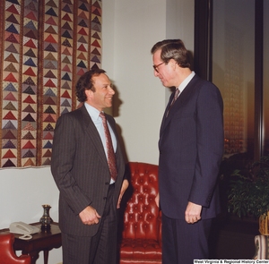 ["Senator John D. (Jay) Rockefeller speaks with an unidentified man in his office."]%
