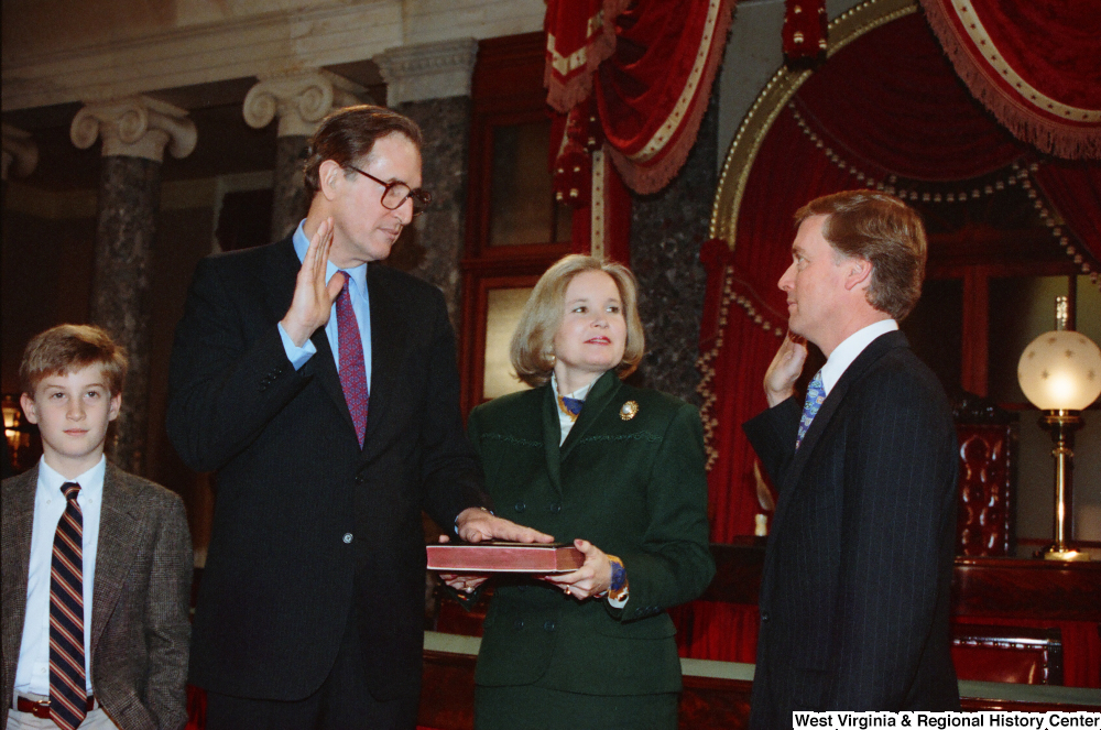 ["Senator John D. (Jay) Rockefeller places his left hand on a bible and raises his right hand to take the oath of office for his second term as Senator from West Virginia."]%