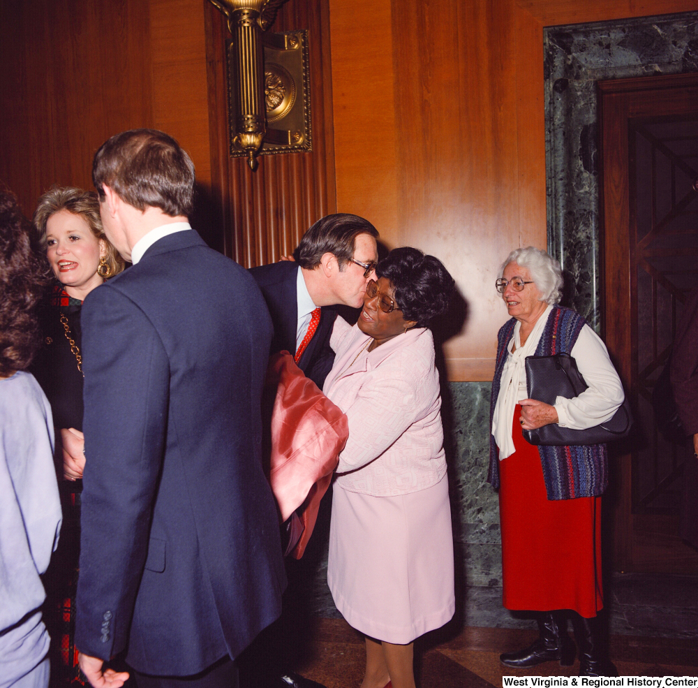 ["Senator John D. (Jay) Rockefeller kisses the cheek of an unidentified supporter at the Senate Swearing-In Ceremony. Sharon Rockefeller can be partially seen to the left."]%