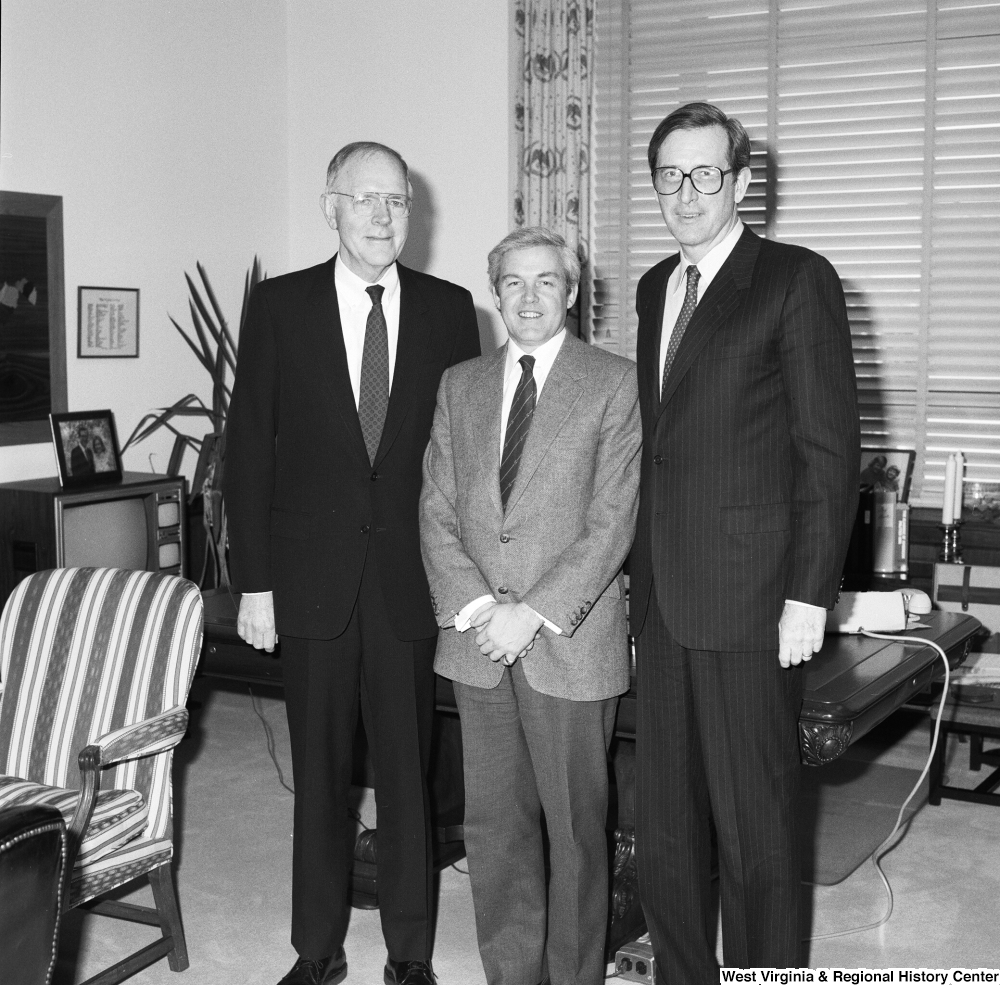 ["Senator John D. (Jay) Rockefeller stands in front of the desk in his office with two representatives from the American Society of Travel Agents."]%