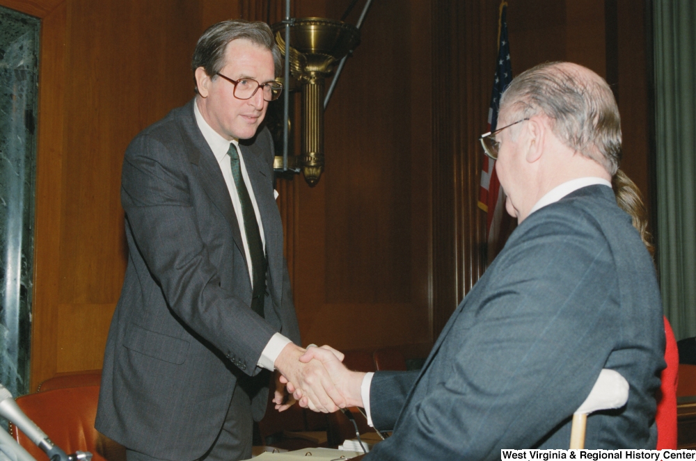 ["Senator John D. (Jay) Rockefeller shakes hands with a man after a Senate sub-committee."]%