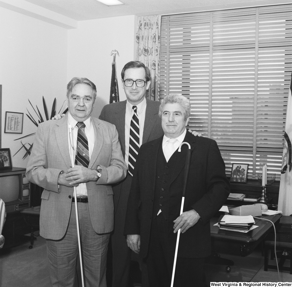 ["Two men from the West Virginia Chapter of the National Federation of the Blind pose for a photograph with Senator John D. (Jay) Rockefeller in his Washington office."]%