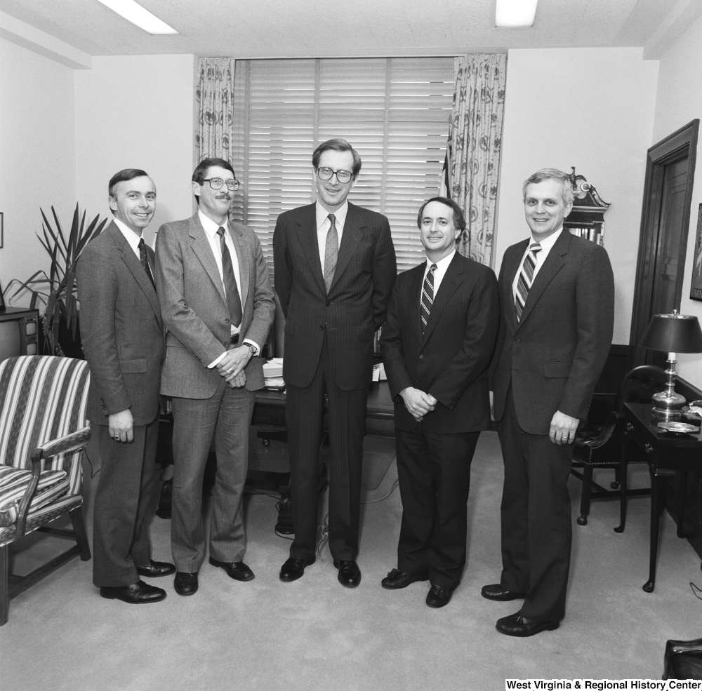 ["Senator John D. (Jay) Rockefeller stands in the middle of a group of four unidentified individuals in his office."]%