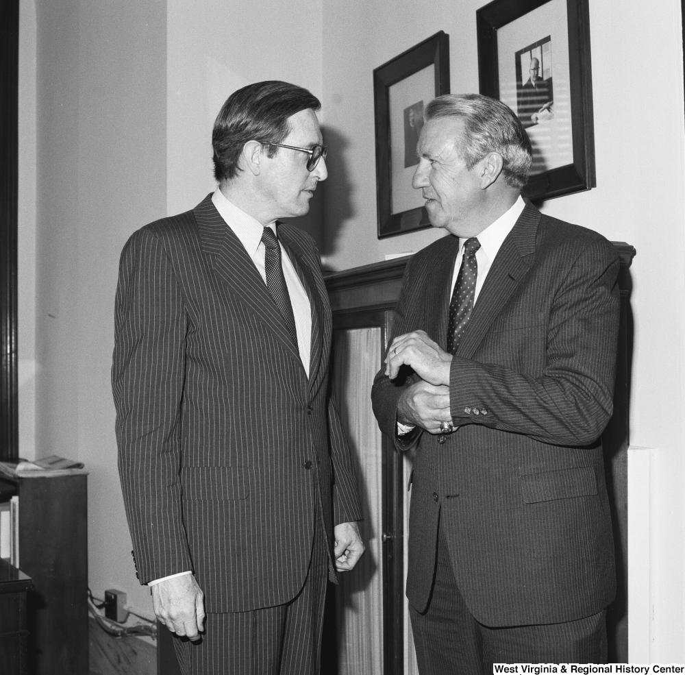 ["Senator John D. (Jay) Rockefeller and an unidentified man speak in the Senator's office."]%