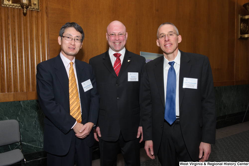 ["Three men stand together at a Washington corporate event."]%