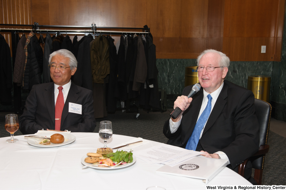 ["Sitting next to an executive from the Toyota Motor Corporation, Senator John D. (Jay) Rockefeller speaks at a Welcome to Washington luncheon."]%