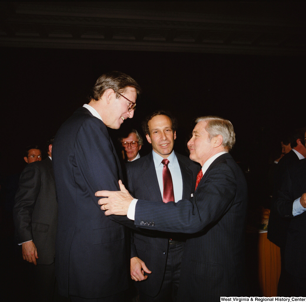["Senator John D. (Jay) Rockefeller shakes hands with an unidentified man at a banquet event at the Senate."]%